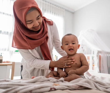 Mother playing with baby on changing table.