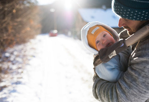 father carrying baby outside in the snow