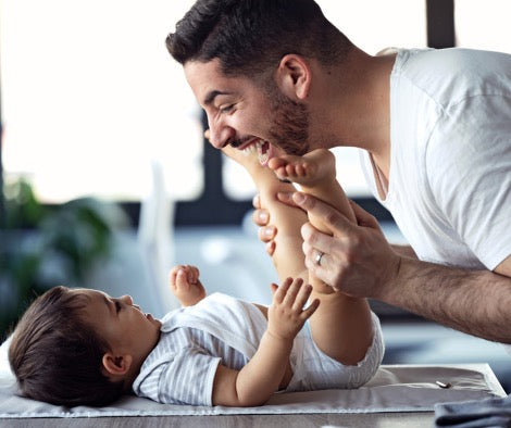 Father playing with baby on changing matt.