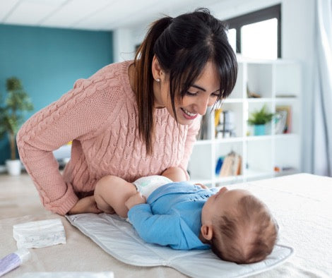 Mother with baby playing on changing table.