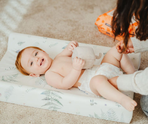 Baby on changing matt getting their Pura eco nappy chnaged.