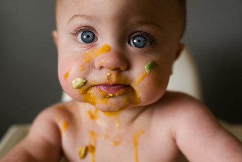 Baby weaning with food on face