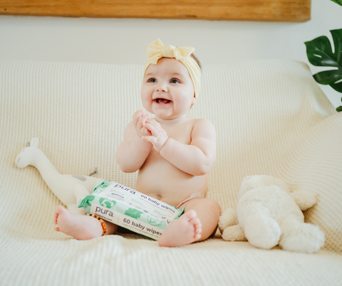 Happy baby holding Pura baby wipes