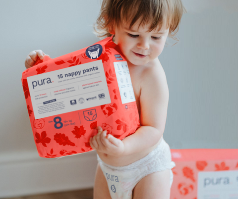 Cute toddler holding Pura nappy pants size 8