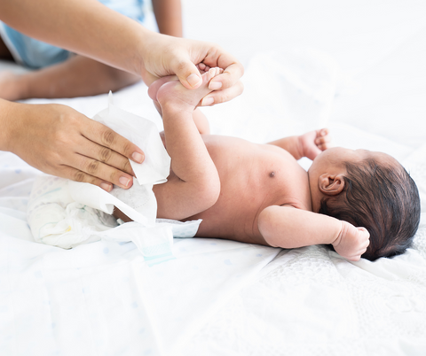 Parent wiping baby's bottom during nappy change.