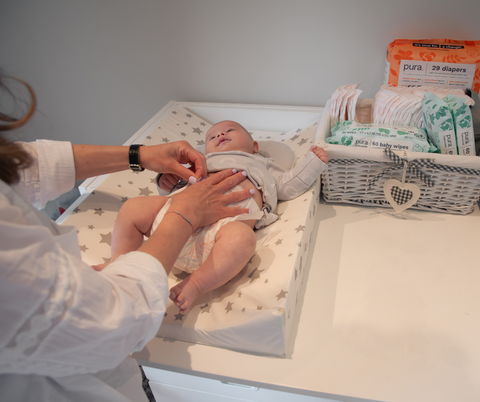 Mother changing baby on changing table.